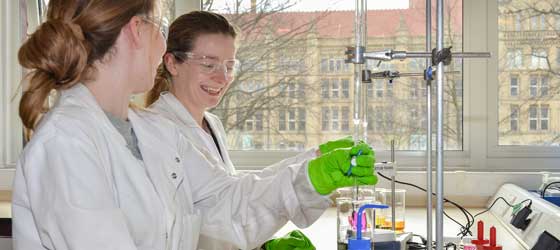 Two lab researchers smiling while attending beacons of liquid