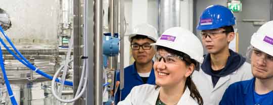 Four students in a lab next to a large cylinder