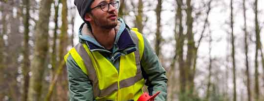 Man outside in a woodland wearing a florescent jacket