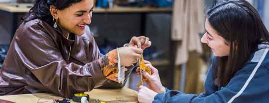 Two female students sat at table constructing small electrical model