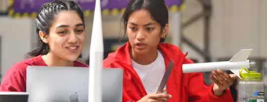 Two female students holding part of a rocket