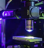 Photonics lab equipment illuminated in purple and green light