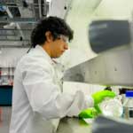 Male pouring clear liquid wearing a lab coat