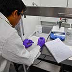 Male in a lab writing on paper