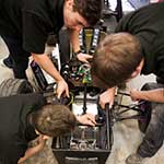 aerial view of three students wiring equipment